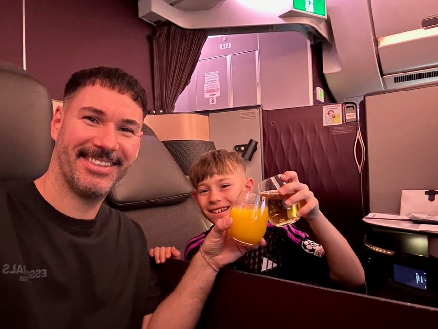 Daniel stößt mit einem Kind in der Business Class an